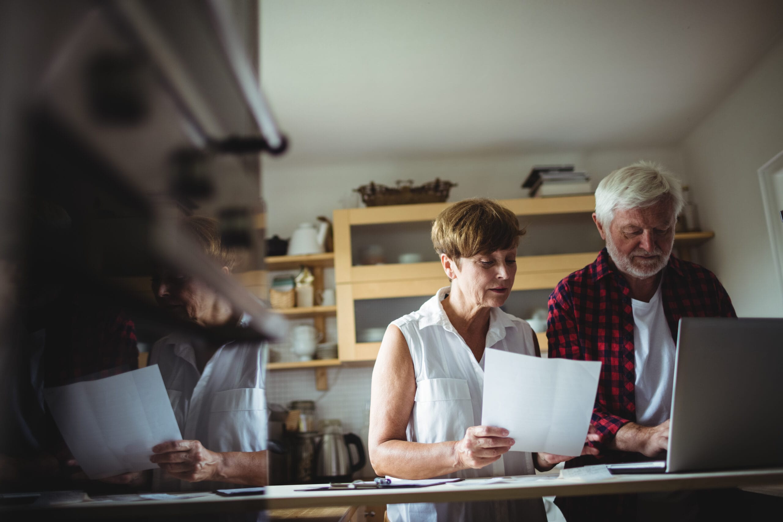 Midlife couple reviewing paperwork together at their kitchen table