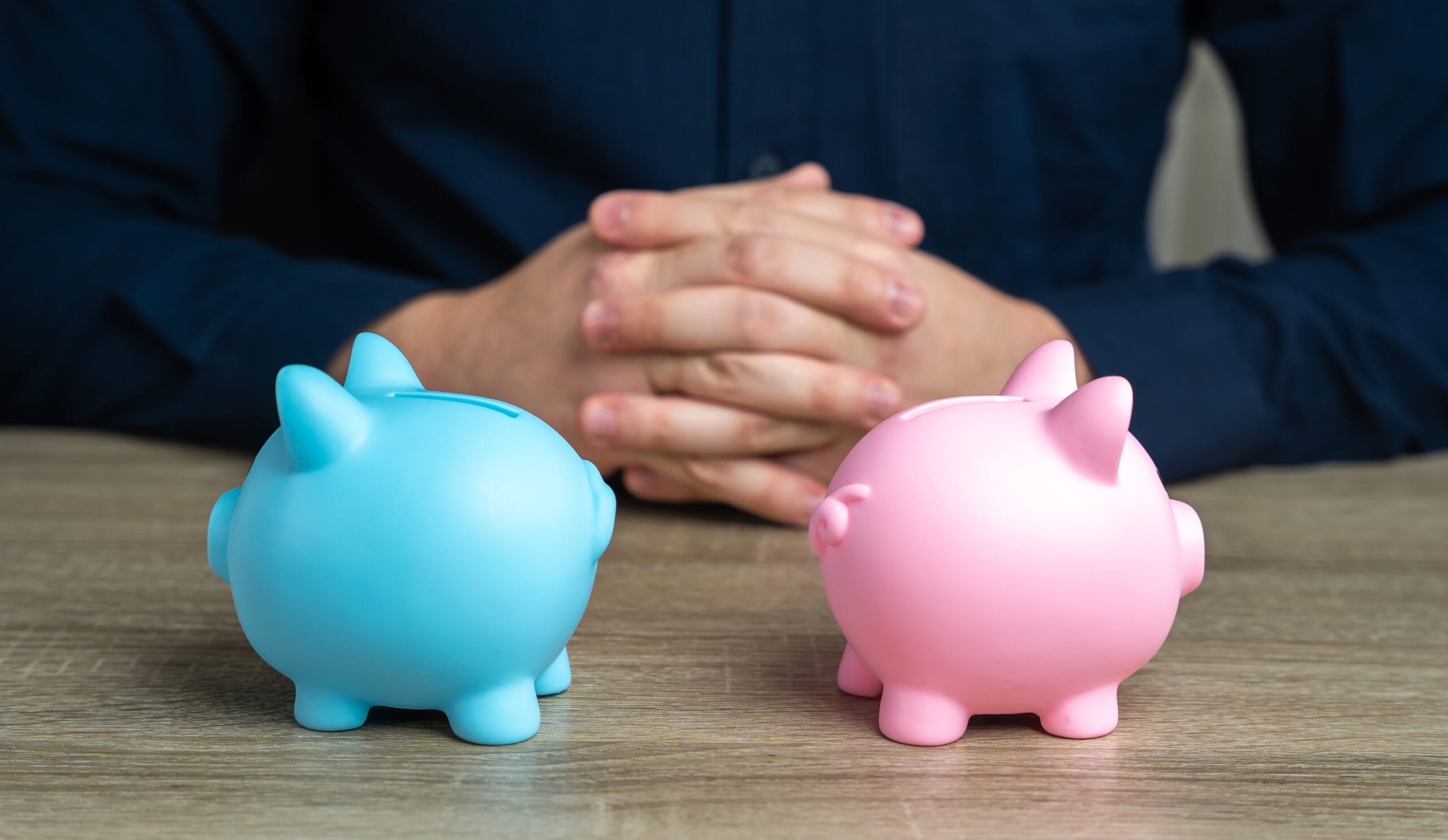Person contemplating two piggy banks, one blue and one pink, symbolising a choice between Cash ISA and Stocks & Shares ISA.